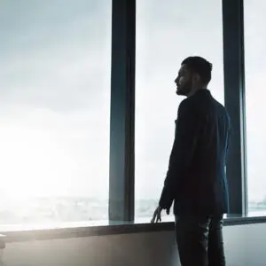 Dirigeant seul face à une fenêtre, en train de réfléchir — solitude du dirigeant et prise de décision