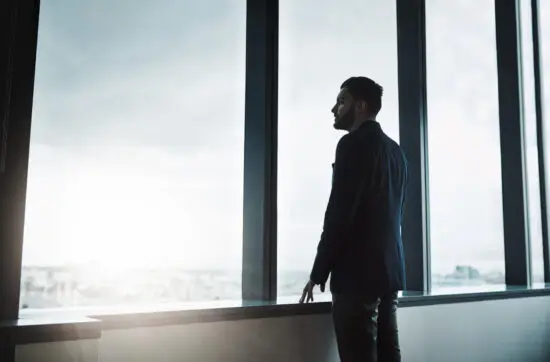 Dirigeant seul face à une fenêtre, en train de réfléchir — solitude du dirigeant et prise de décision