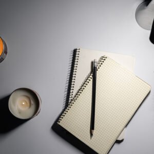 Carnet ouvert avec une liste manuscrite sous une lampe de bureau, le soir